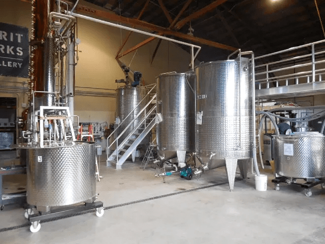 Industrial brewery tanks and equipment inside building.